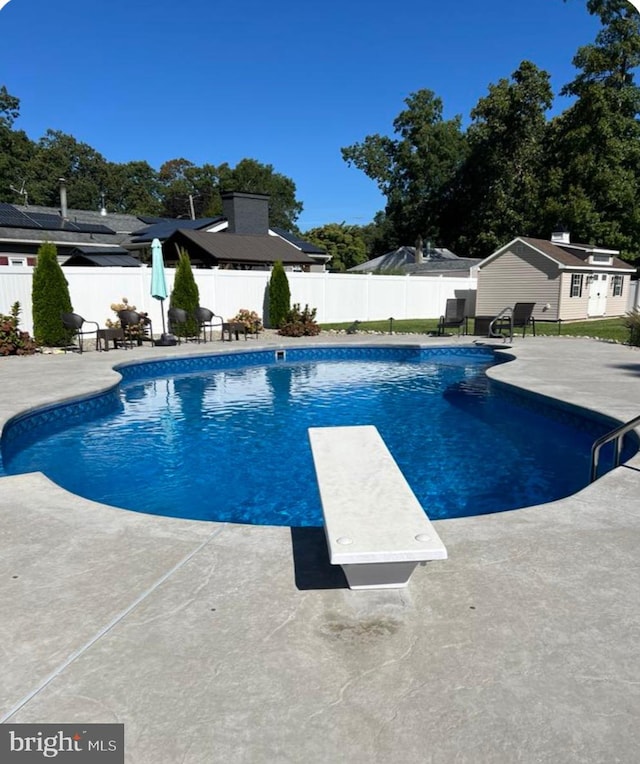 view of swimming pool with a diving board and a patio