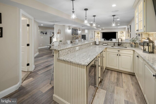 kitchen featuring kitchen peninsula, sink, and light stone counters