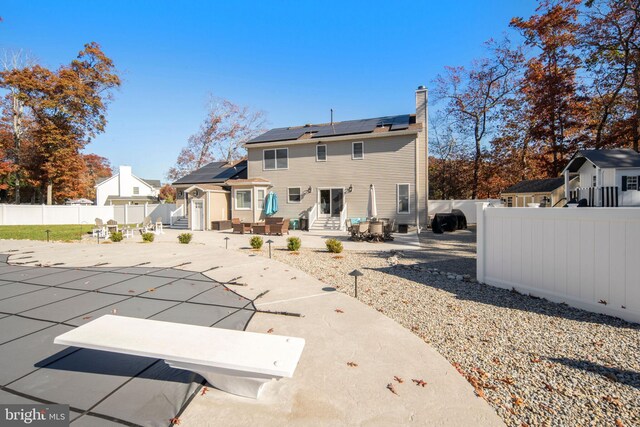 back of property featuring a covered pool, a patio, and solar panels