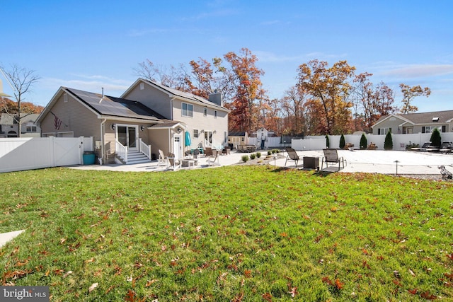 back of property featuring solar panels, a patio, and a yard