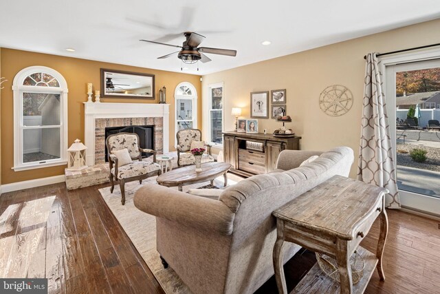 living room with a fireplace, dark hardwood / wood-style flooring, and ceiling fan