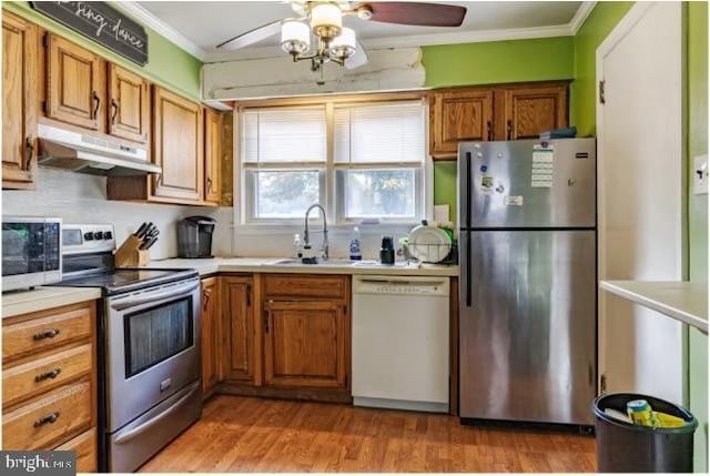 kitchen with light hardwood / wood-style floors, sink, appliances with stainless steel finishes, and ornamental molding