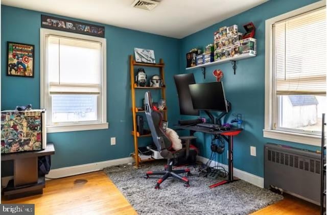 home office with radiator, wood finished floors, and baseboards