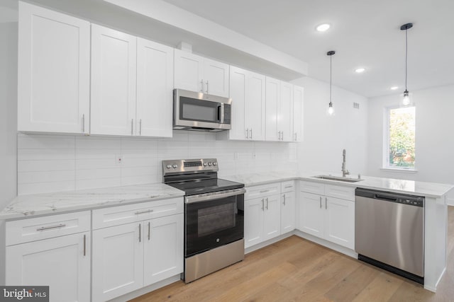 kitchen featuring sink, light hardwood / wood-style flooring, hanging light fixtures, stainless steel appliances, and white cabinets