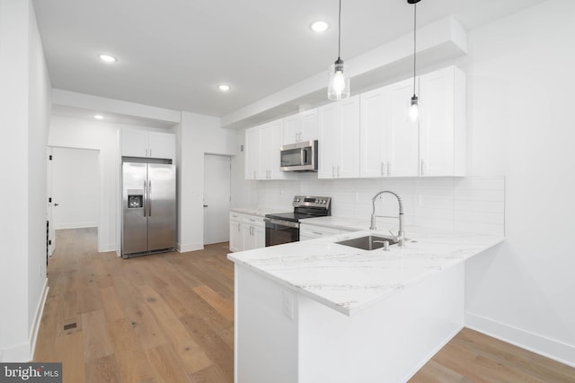 kitchen with white cabinetry, stainless steel appliances, sink, backsplash, and hanging light fixtures