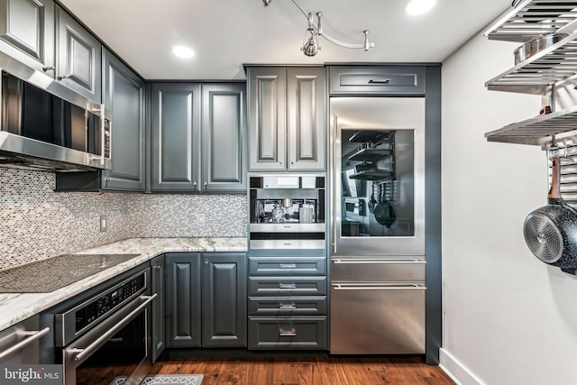 kitchen featuring light stone countertops, dark wood-type flooring, and appliances with stainless steel finishes