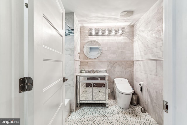 bathroom featuring vanity, toilet, and tile walls