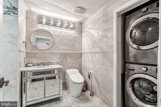 bathroom featuring vanity, toilet, tile walls, and stacked washer / drying machine