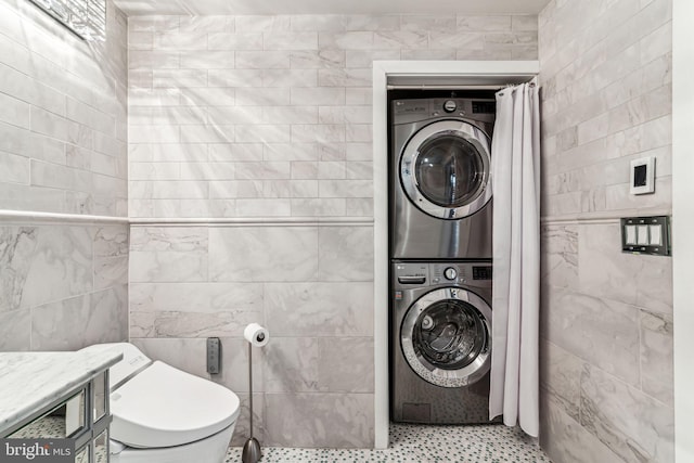 clothes washing area featuring stacked washer / dryer and tile walls