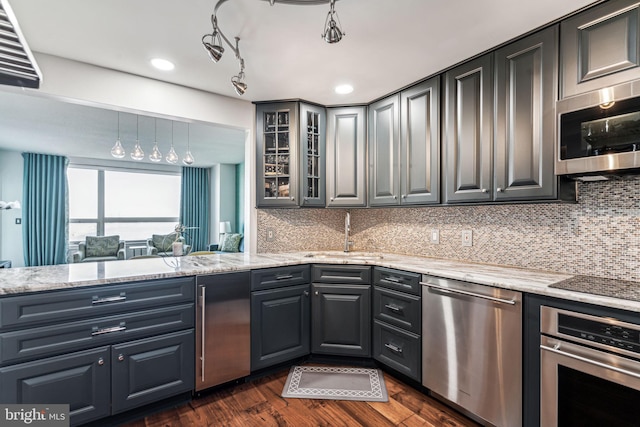 kitchen with sink, dark wood-type flooring, stainless steel appliances, tasteful backsplash, and light stone counters