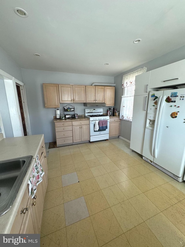 kitchen with light brown cabinets, white appliances, and sink