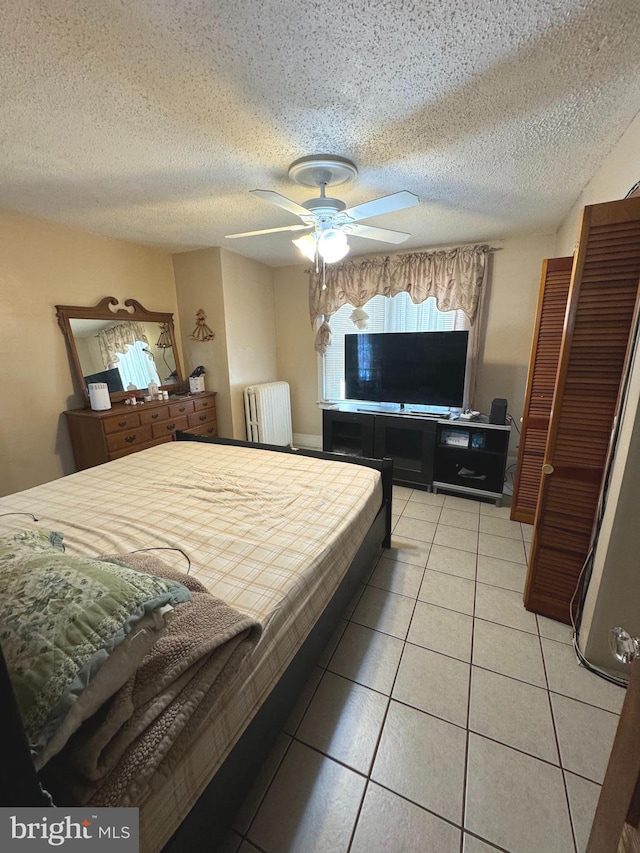 bedroom with light tile patterned flooring, radiator, a textured ceiling, and ceiling fan