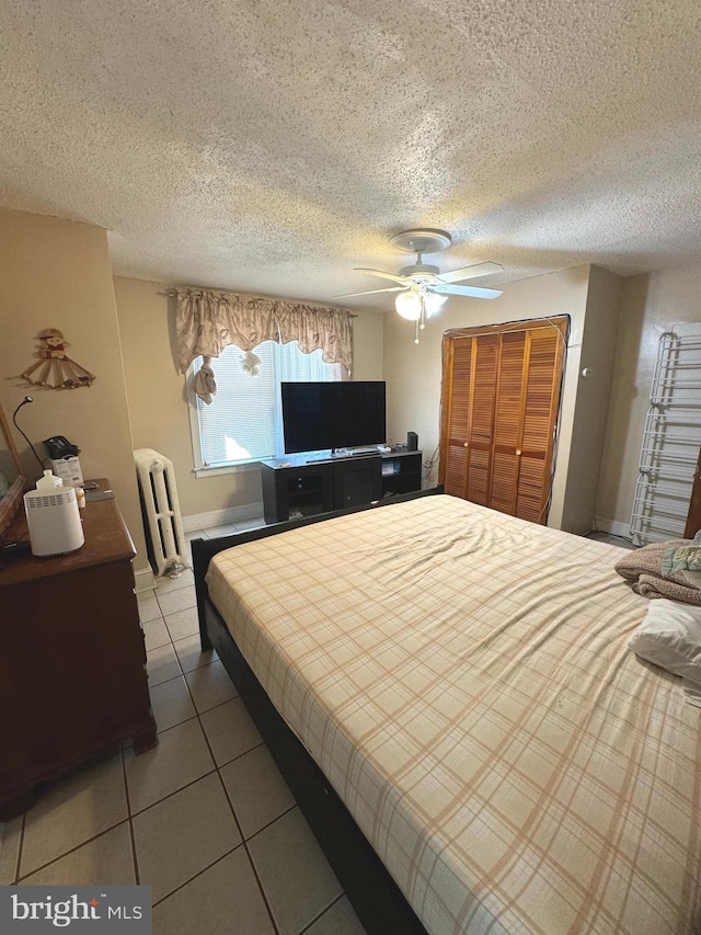 bedroom featuring a closet, radiator heating unit, tile patterned floors, a textured ceiling, and ceiling fan