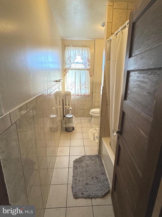 bathroom with toilet, shower / tub combo with curtain, tile walls, and tile patterned floors