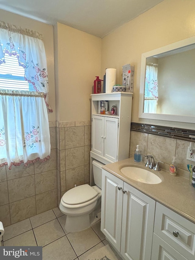 bathroom with toilet, vanity, tile walls, and tile patterned flooring