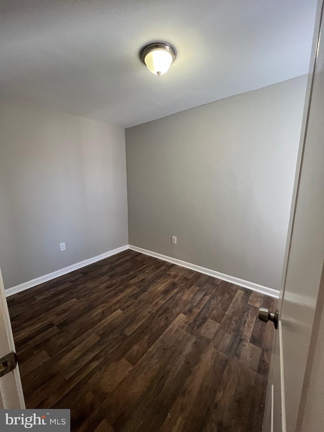 unfurnished room with dark wood-type flooring