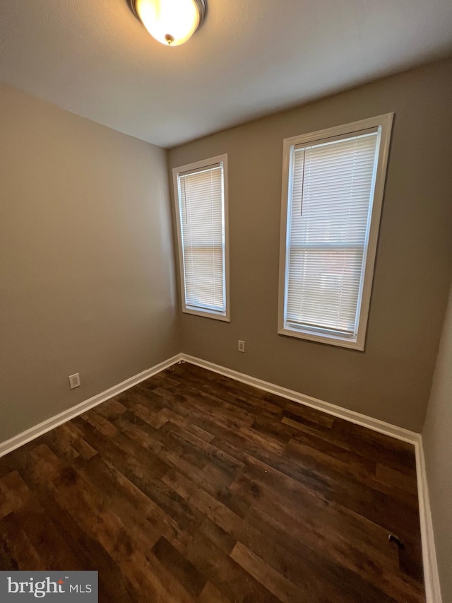 unfurnished room featuring dark wood-style floors and baseboards