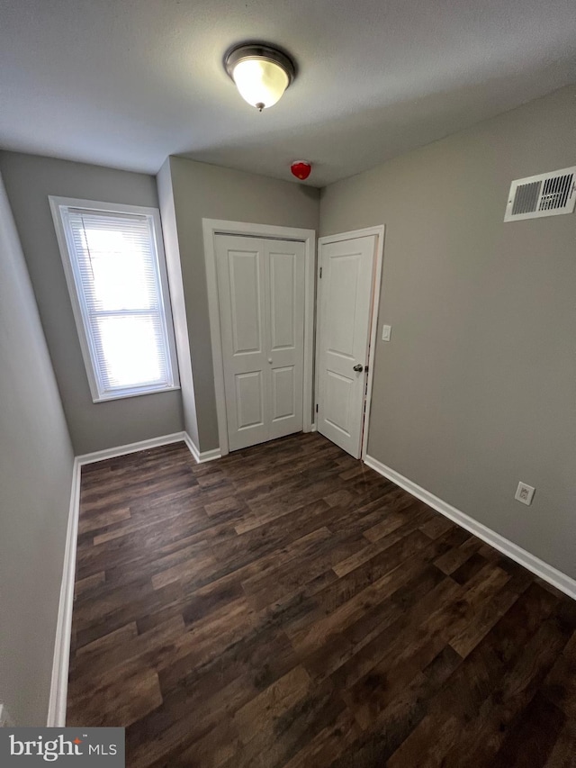 unfurnished room featuring dark wood-type flooring and baseboards