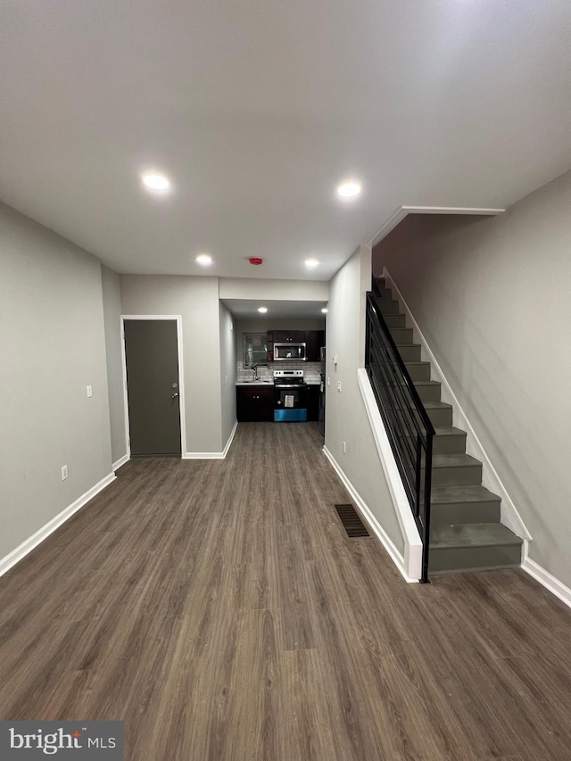 unfurnished living room with stairway, dark wood-style flooring, baseboards, and recessed lighting