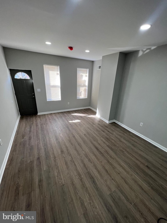 unfurnished living room with baseboards, dark wood-type flooring, and recessed lighting