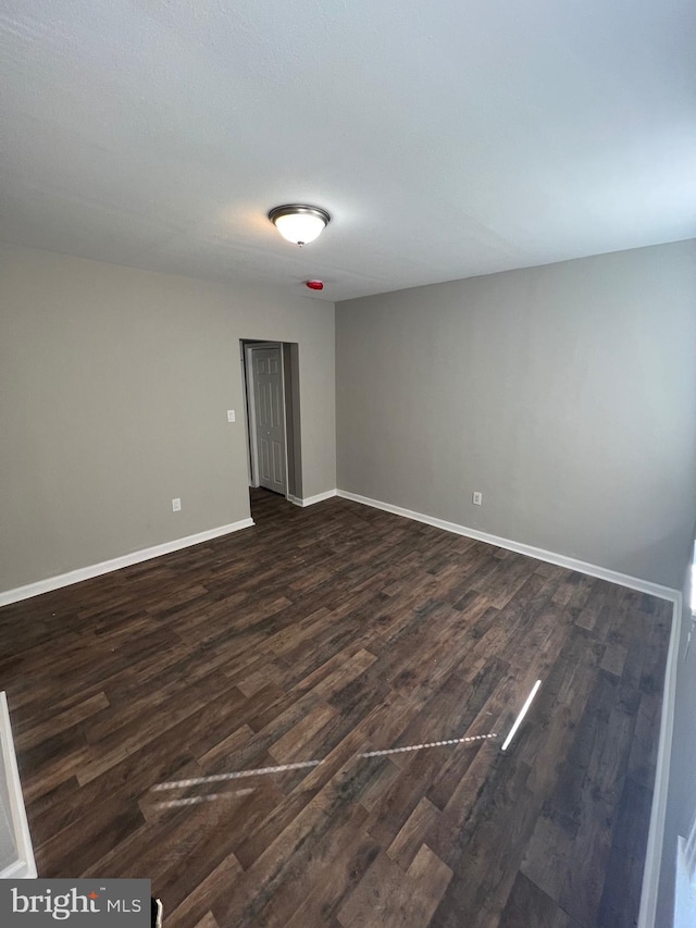empty room featuring dark wood finished floors and baseboards