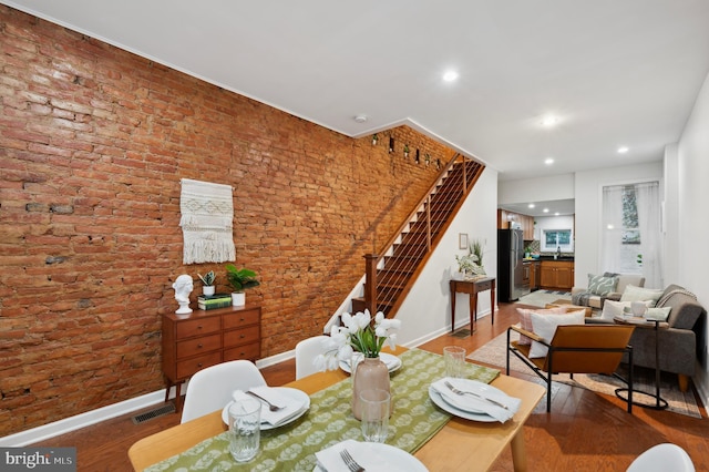 dining area featuring hardwood / wood-style flooring and brick wall