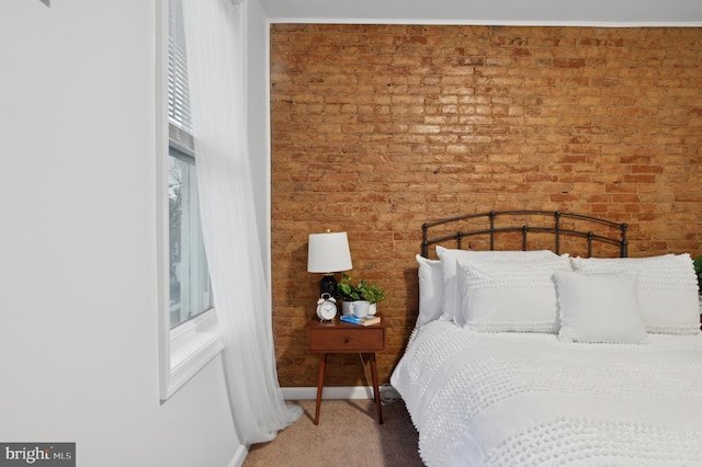 carpeted bedroom featuring brick wall