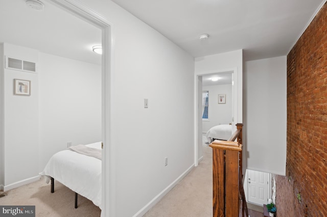 corridor featuring light colored carpet and brick wall