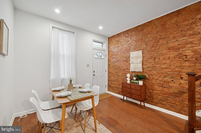 dining area featuring plenty of natural light, brick wall, and hardwood / wood-style flooring