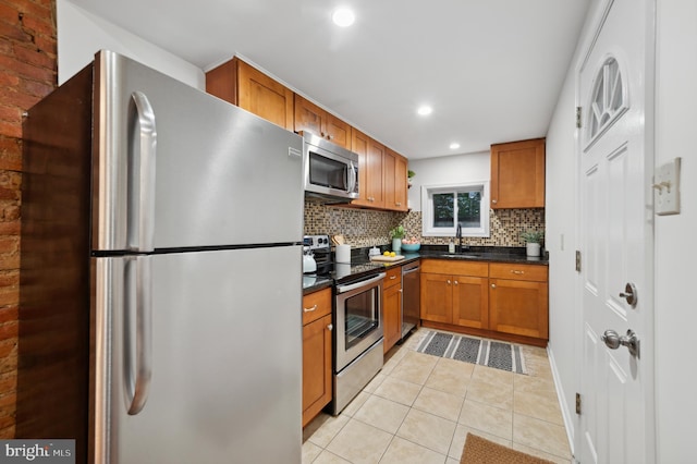 kitchen with backsplash, appliances with stainless steel finishes, sink, and light tile patterned floors