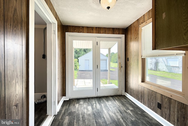 doorway to outside featuring dark hardwood / wood-style floors, wooden walls, and a textured ceiling