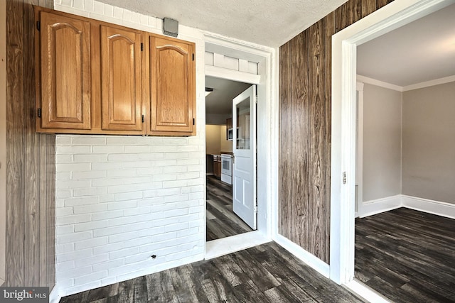 kitchen with crown molding, a textured ceiling, dark hardwood / wood-style floors, wooden walls, and white stove