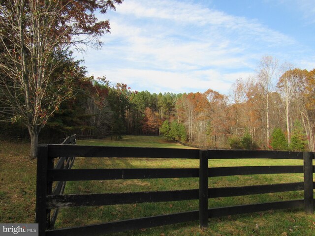 view of gate featuring a lawn and a rural view