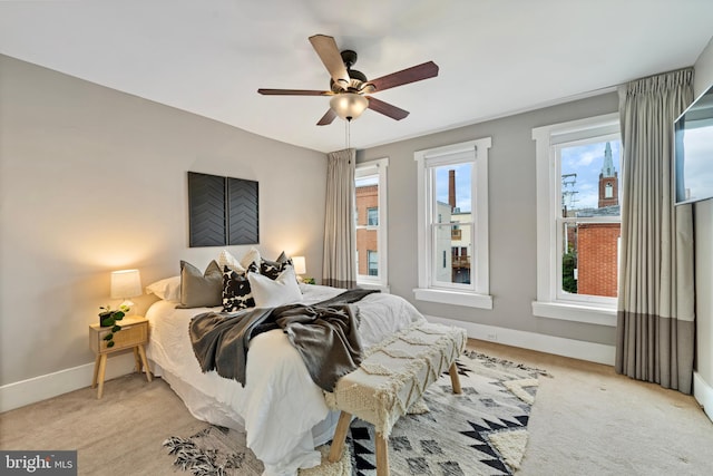 carpeted bedroom featuring multiple windows and ceiling fan