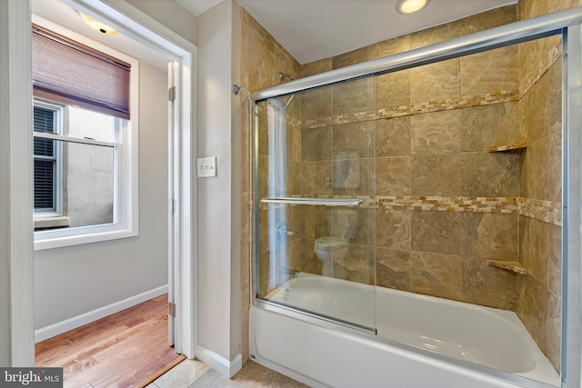 bathroom featuring hardwood / wood-style floors and bath / shower combo with glass door