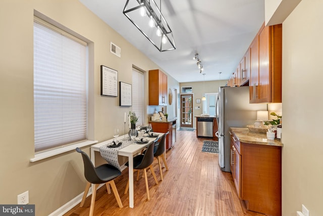 kitchen with light stone counters, light wood-type flooring, appliances with stainless steel finishes, and track lighting