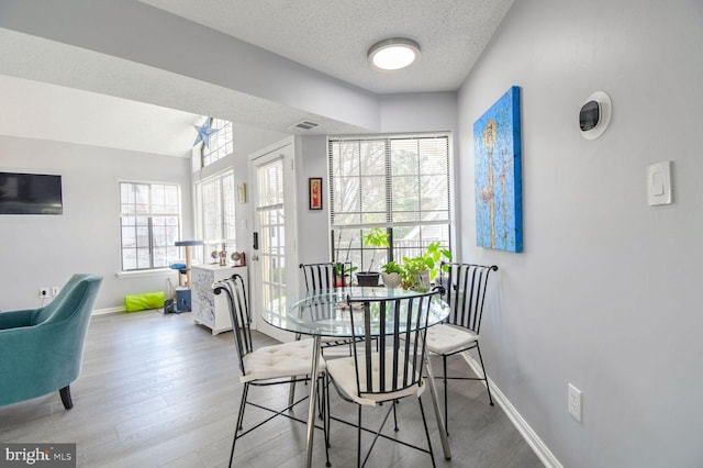 dining space with light wood-type flooring and a textured ceiling