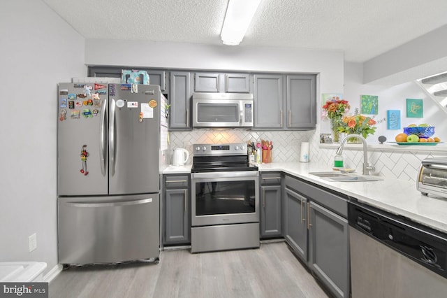 kitchen featuring gray cabinets, sink, and appliances with stainless steel finishes