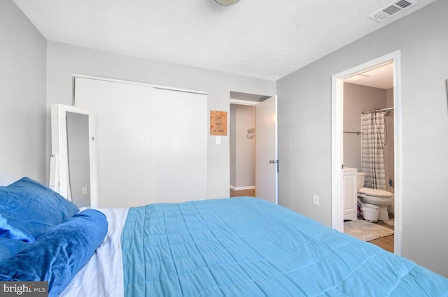 bedroom with ensuite bath, a textured ceiling, and a closet