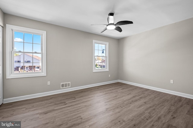 spare room featuring dark wood-type flooring, ceiling fan, and plenty of natural light