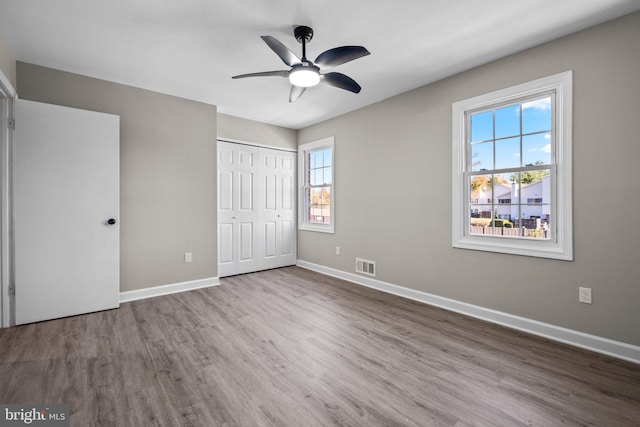 unfurnished bedroom featuring hardwood / wood-style floors, ceiling fan, and a closet