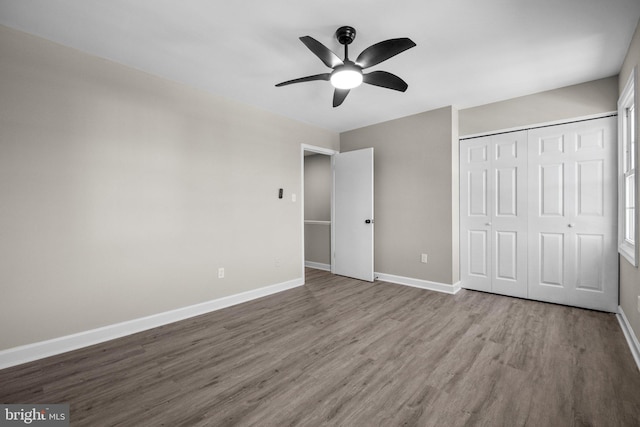 unfurnished bedroom with ceiling fan, wood-type flooring, and a closet