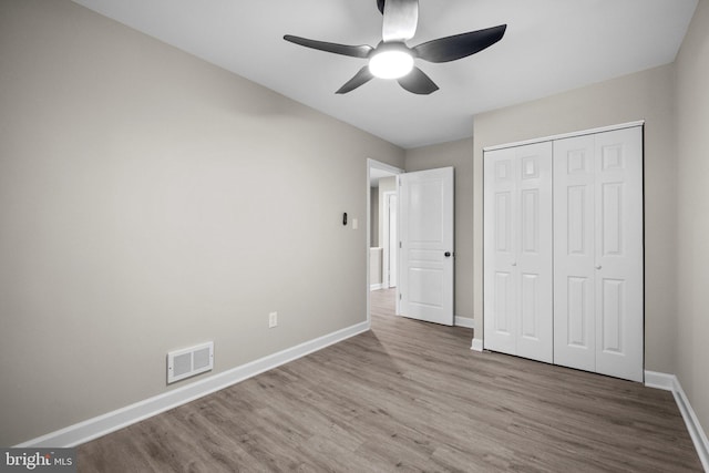 unfurnished bedroom featuring a closet, light hardwood / wood-style floors, and ceiling fan