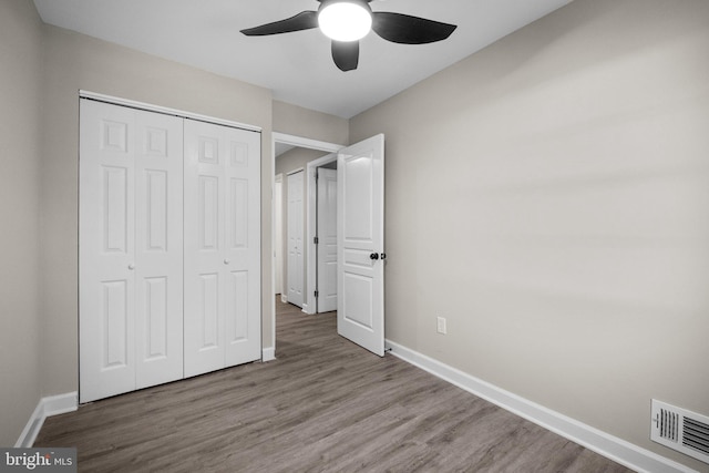 unfurnished bedroom with ceiling fan, a closet, and light wood-type flooring