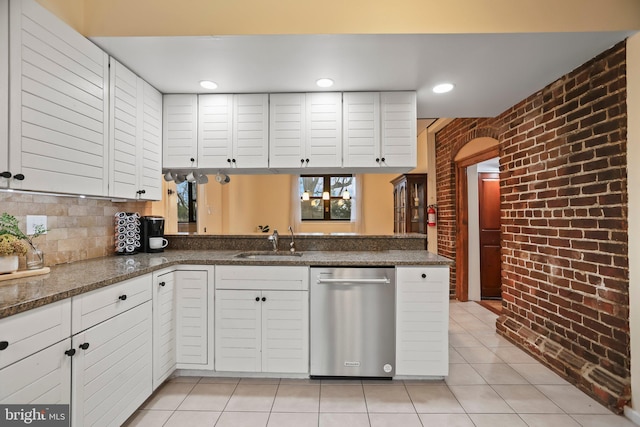 kitchen featuring kitchen peninsula, brick wall, white cabinetry, stainless steel dishwasher, and light tile patterned flooring