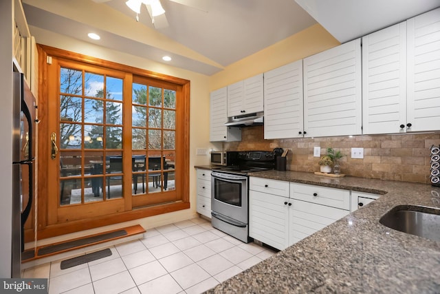 kitchen with stainless steel appliances, decorative backsplash, lofted ceiling, white cabinets, and dark stone countertops