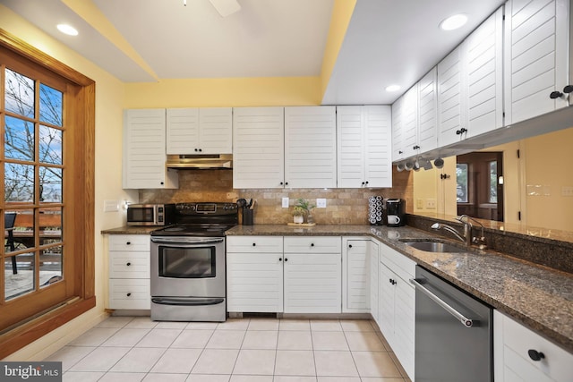 kitchen with sink, white cabinets, backsplash, dark stone counters, and appliances with stainless steel finishes