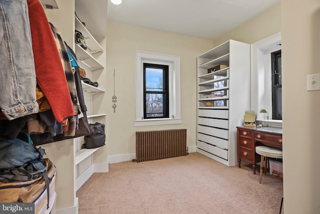 walk in closet with light colored carpet and radiator heating unit