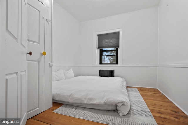 bedroom with radiator heating unit and light wood-type flooring