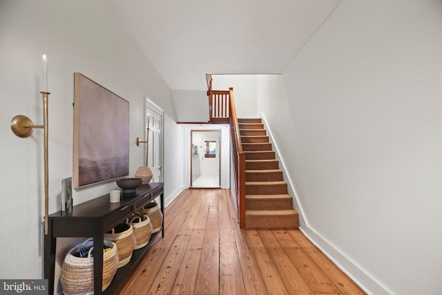 hallway featuring lofted ceiling and light wood-type flooring